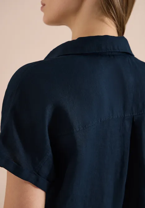 Person von hinten in einem dunkelblauen Kurzarmhemd mit dekorativem Rückenabnäher.
