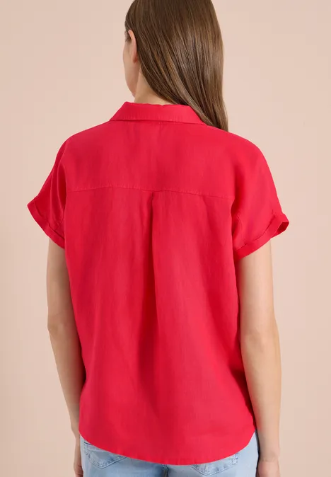 Frau von hinten in einer roten, kurzärmeligen Bluse mit umgeschlagenen Ärmeln