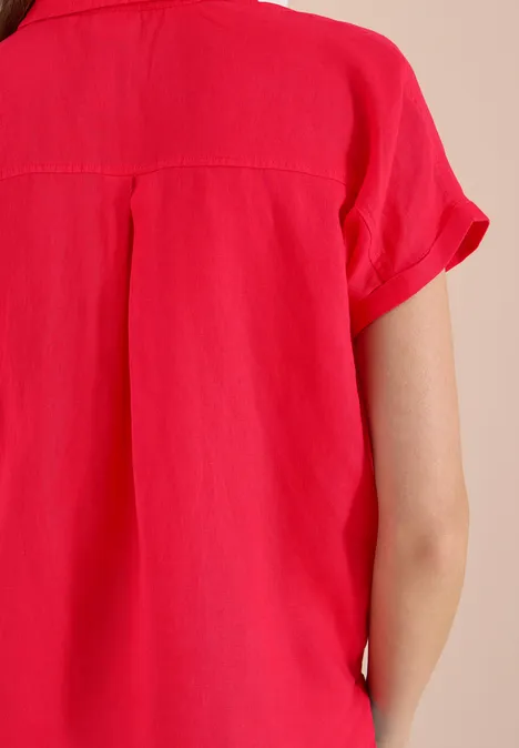 Rückansicht einer Person in roter Bluse mit kurzen Ärmeln aus leichtem Stoff.
