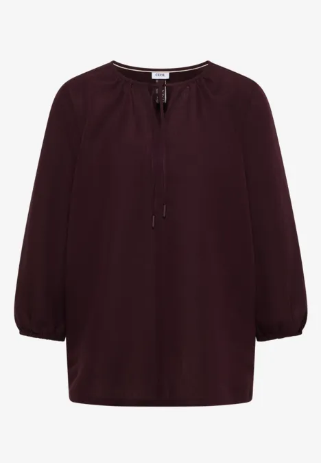 Bordeauxrote Bluse mit 3/4-Ärmeln und Schnürung am Rundhalsausschnitt.