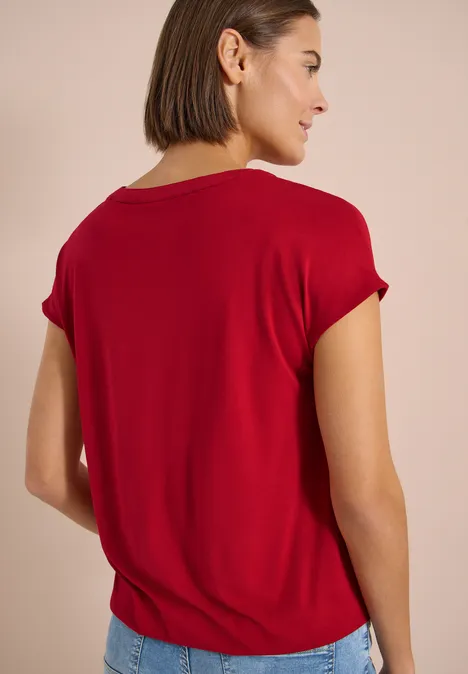 Frau mit rotem T-Shirt von hinten vor hellem Hintergrund