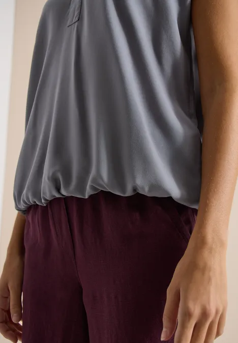 Dunkelgraue fließende Bluse kombiniert mit locker sitzender bordeauxroter Hose, seitliche Armansicht.