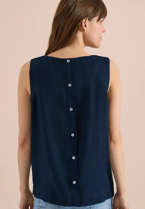 Femme de dos portant un top sans manches bleu marine avec boutons dans le dos.
