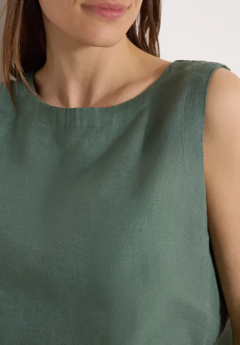 Nahaufnahme des Oberkörpers einer Frau in ärmellosem dunkelgrünen Leinenoberteil
