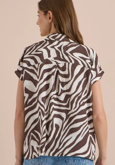 Kurzarm Hemdbluse mit Zebra-Print brown cacao Frau von hinten trägt kurzärmeliges Hemd mit braun-weißem Zebramuster.