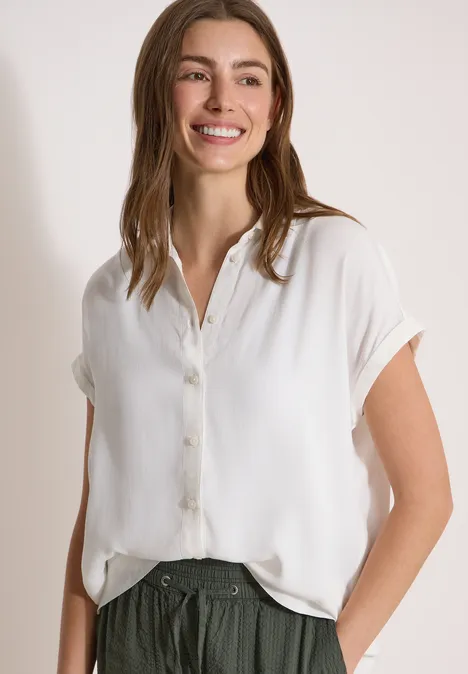 Chemisier à manches courtes uni vanilla white Personne vêtue d’un chemisier blanc ample à manches courtes, une main dans la poche du pantalon.