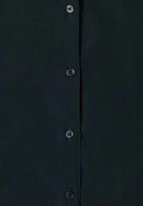 Chemisier à manches courtes uni palm breeze green Vêtement noir avec patte de boutonnage et boutons noirs sur tissu sombre.