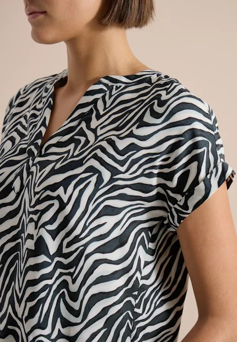 Damenbluse mit schwarz-weißen Zebramuster, kurzärmelig und locker geschnitten.