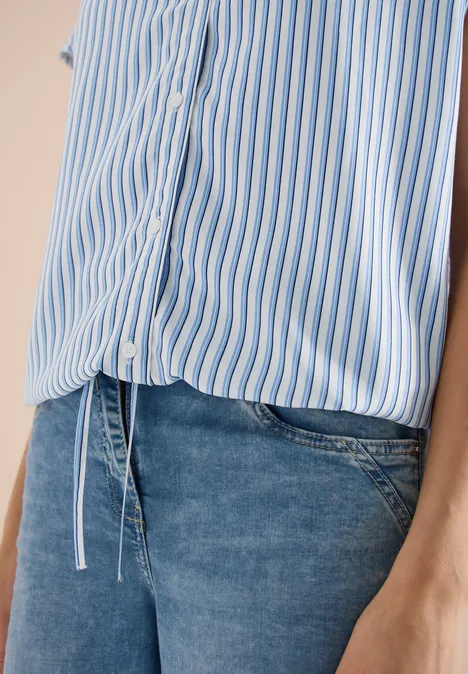 Ansicht eines Oberkörpers in hellblau-weiß gestreifter Bluse und blauen Jeans.