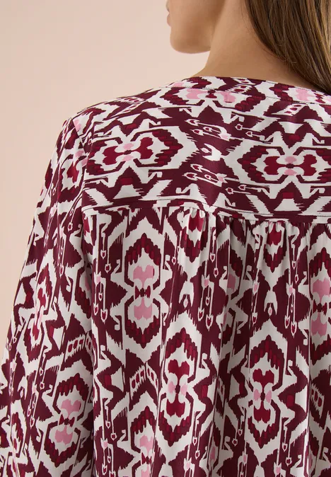 Rückansicht einer fließenden Bluse mit bordeaux-weißem Ikat-Muster.