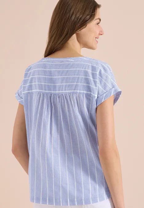 Junge Frau von hinten in hellblauer, weiß gestreifter Bluse mit kurzen Ärmeln.