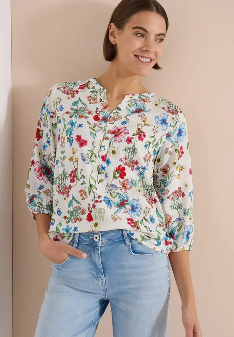 Femme en chemisier blanc à fleurs et jean bleu clair