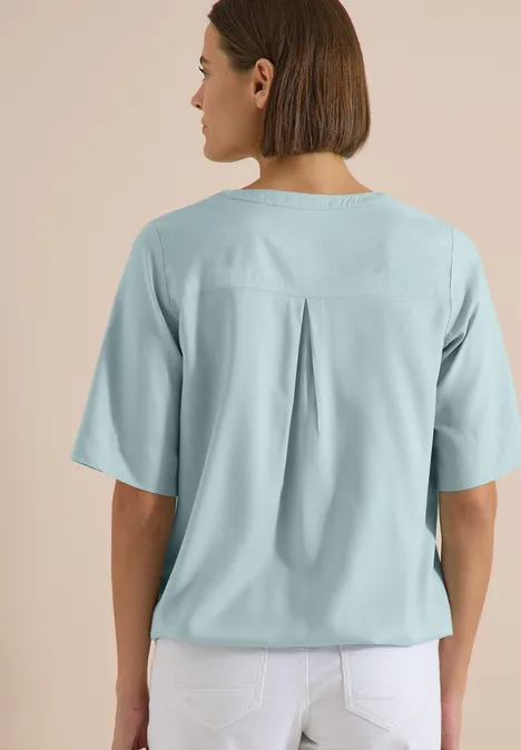 Kurzarm Bluse mit Split Neck crystal mint Rückenansicht einer Frau mit kinnlangen Haaren, hellblauer Bluse mit Rückenfalte und weißen Hosen.