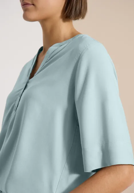 Kurzarm Bluse mit Split Neck crystal mint Profilansicht einer Frau in pastellblauer, locker sitzender Bluse mit V-Ausschnitt und halb langen Ärmeln.