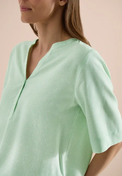Frau mit pastellgrünem, geripptem Oberteil und kurzen Ärmeln