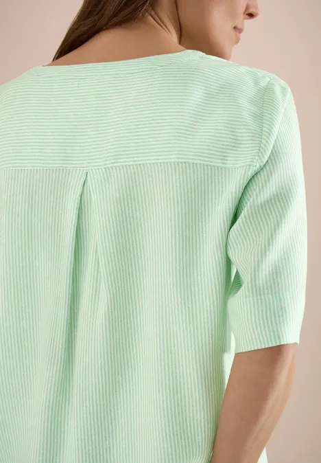 Eine Frau von hinten in einem mintgrünen, gestreiften Oberteil mit halblangen Ärmeln.