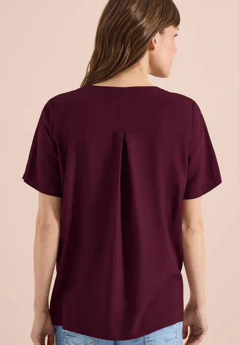 Rückenansicht einer Frau in lockerem, kurzärmligem, burgunderrotem Oberteil