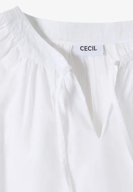 Witte damestop met amandelvormige halslijn en merklabel "CECIL" bij de kraag