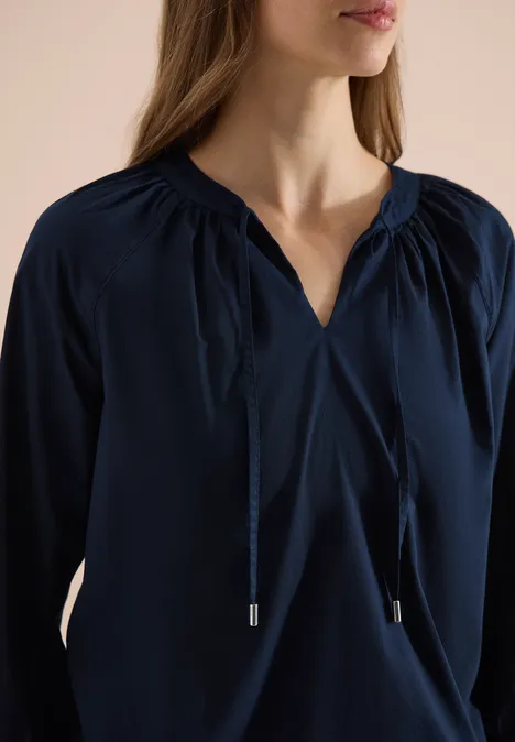 Dunkelblaue Damenbluse mit V-Ausschnitt und Kordelzügen.