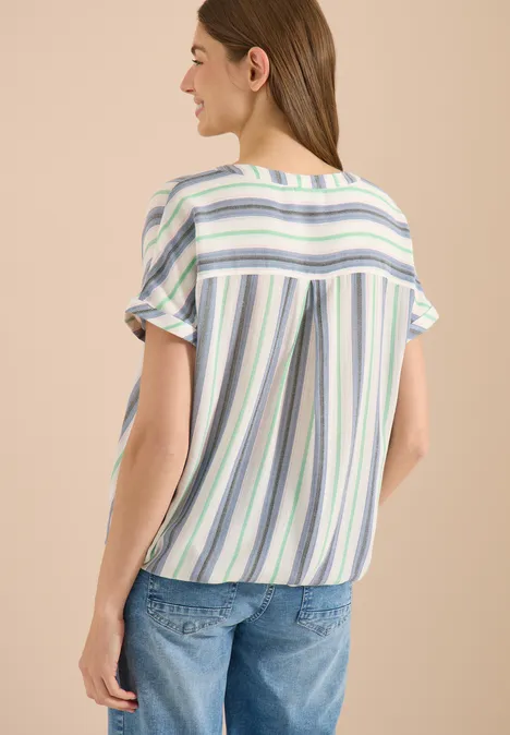 Frau von hinten in gestreifter Kurzarmbluse und Jeans.