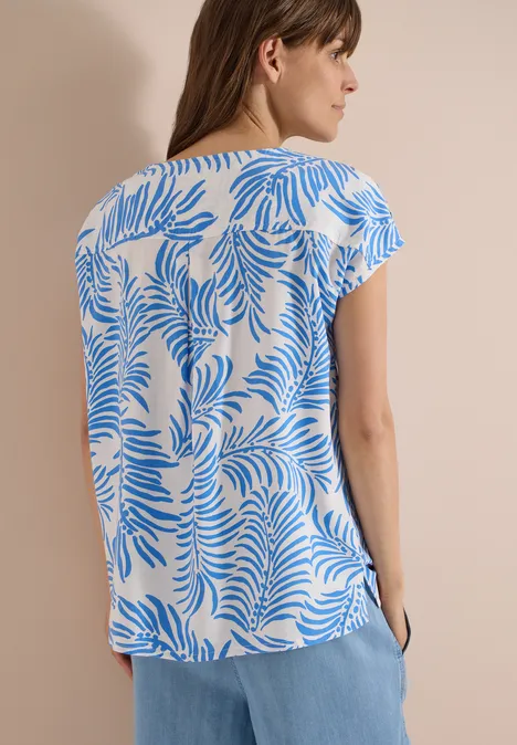 Dropped Shoulder Shirt mit Print vanilla white Frau von hinten in weiß-blau gemusterter Bluse und hellblauen Hosen vor neutralem Hintergrund.