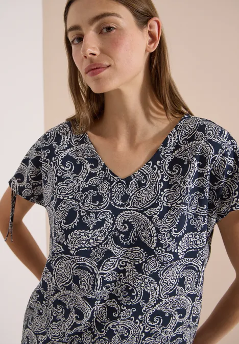 Overhemd met gerimpeld detail universal blue Vrouw draagt donkerblauw overhemdje met paisleyprint en V-hals tegen neutrale achtergrond.