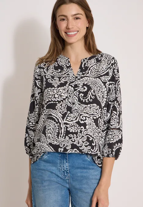 Tuniek met 3/4-mouwen en print Black Een vrouw draagt een zwart-witte blouse met patroon en een blauwe spijkerbroek.