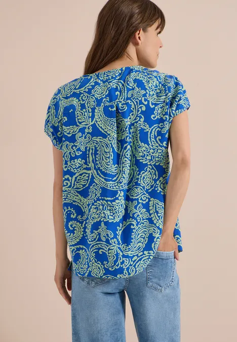 Blusenshirt mit Rundhals und Print surf blue Frau von hinten in blauer Kurzarmbluse mit gelbgrünem Paisley-Muster und Jeans.