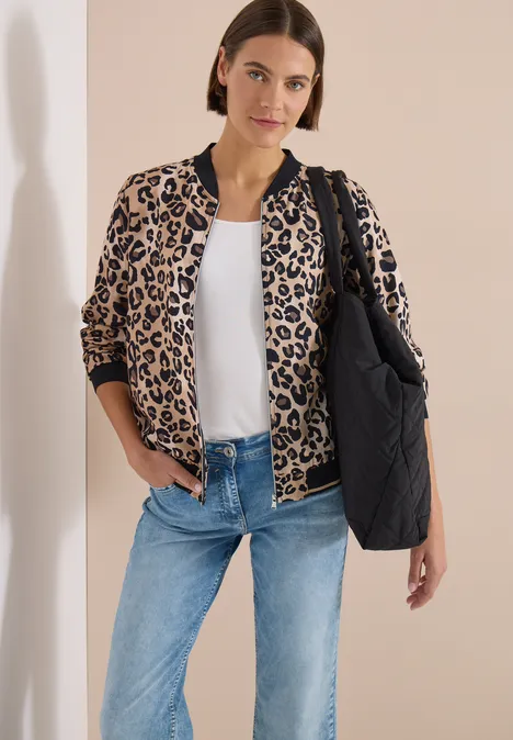 Leichter Blouson mit Zipper und Leo-Print urban taupe Frau mit Leo-Blouson, weißem Shirt, Jeans und schwarzer gesteppter Tasche vor hellem Hintergrund.