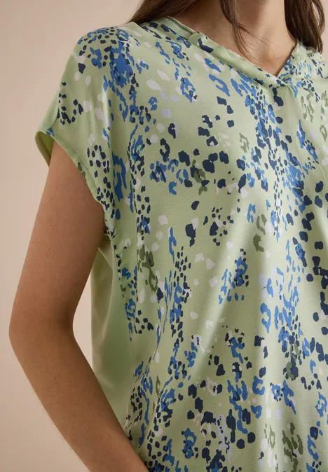 Chemisier à manches courtes avec mélange de textures raw matcha lime Eine hellgrüne Bluse mit abstrakten blauen Tupfen.