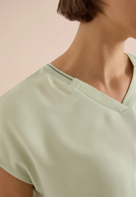 Nahaufnahme eines hellgrünen V-Ausschnitt-Shirts, das Schulter und Halsbereich zeigt.