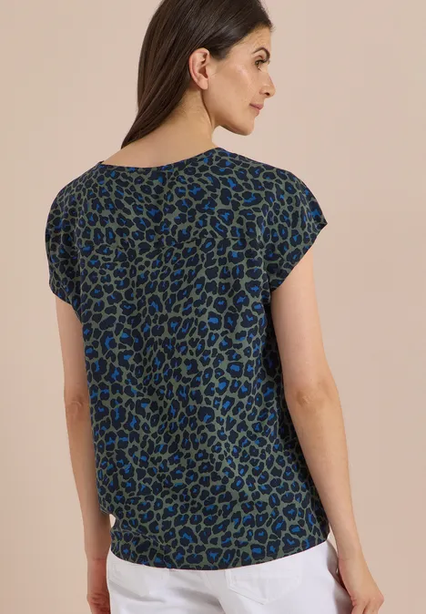 Chemisier à épaules tombantes avec nœud dried olive green Frau von hinten in kurzärmeliger Bluse mit blau-schwarzem Leopardenmuster.
