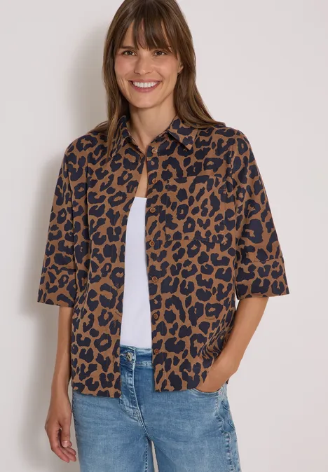 Overhemd met korte mouwen van corduroy met luipaardprint creamy mocha Vrouw lacht, draagt een bruin leopardprint kort overhemd over een wit topje met jeans.