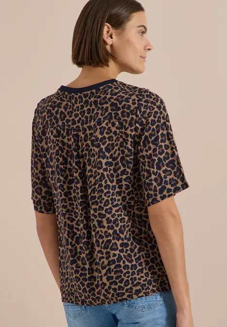 Blouse met korte mouwen en luipaardprint creamy mocha Frau mit Bob trägt legeres braun-schwarzes Leo-T-Shirt und Jeans, Rückenansicht mit seitlich gedrehtem Kopf.