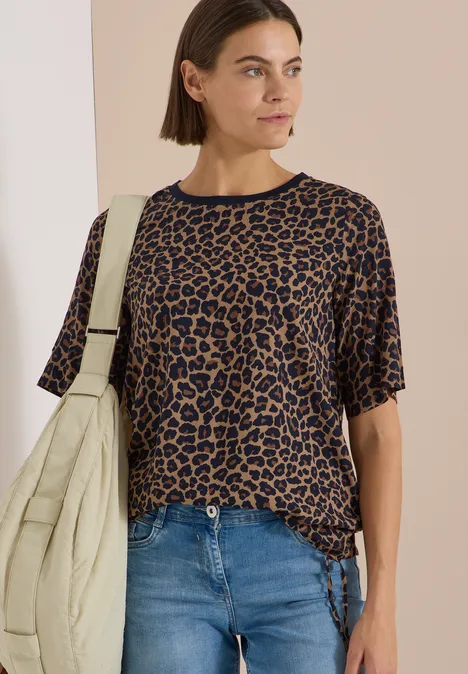 Blouse met korte mouwen en luipaardprint creamy mocha Frau in kurzärmeligem, braun-schwarzem Leo-Shirt mit Jeans und beiger Stepp-Umhängetasche.