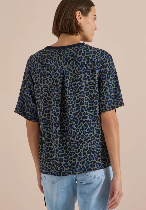 Blouse met korte mouwen en luipaardprint dried olive green Frau von hinten in lockerem, kurzärmeligem Shirt mit blau-schwarzem Animal-Print und Jeans.