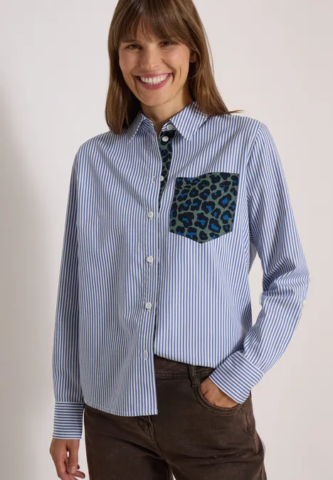 Hemdbluse mit Streifen und Leo-Brusttasche blouse blue Lächelnde Frau in blau-weiß gestreiftem Hemd mit auffälliger Leoparden-Tasche und brauner Hose.