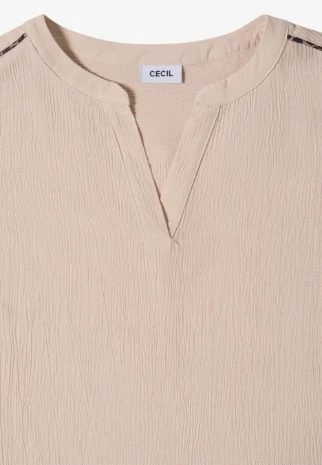 Beige Damenbluse mit leicht strukturierter Oberfläche, V-Ausschnitt und langen Ärmeln.