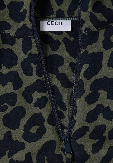 Detailaufnahme eines olivgrünen Fleckenmusters auf einem Kleidungsstück mit weißem Label 'CECIL'.