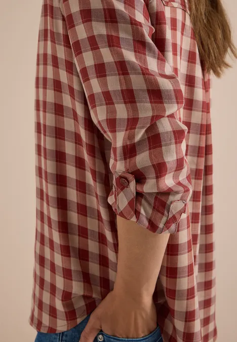 Chemisier à manches longues à carreaux dark russet red Personne porte une chemise à carreaux rouge et blanche, manches retroussées.
