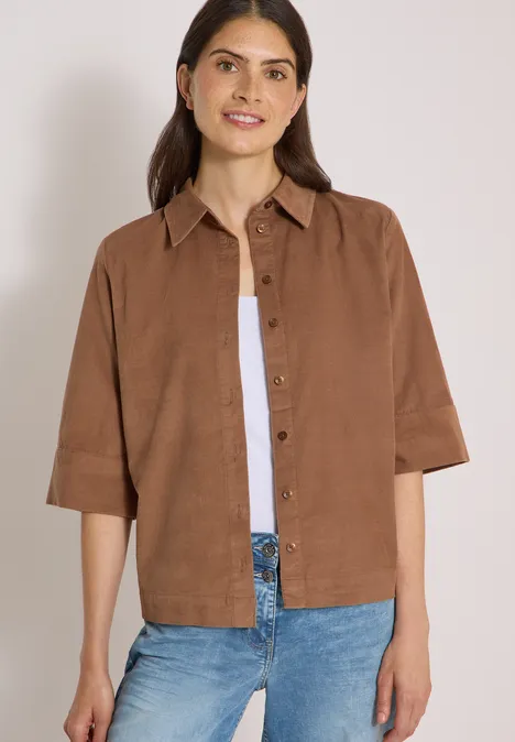 Overhemd met korte mouwen in effen kleur creamy mocha Vrouw met kastig bruin linnen overhemd, wit topje en blauwe jeans, glimlachend