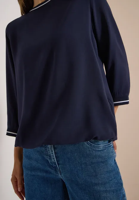 Frau trägt dunkelblauen Dreiviertelarm-Pullover mit Jeans