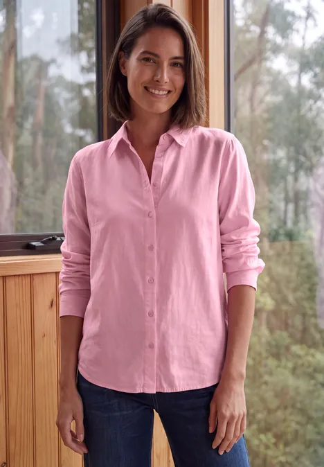 Langarm Hemdbluse mit Knopfleiste mellow rose Eine Frau in rosa Hemd und Jeans lächelt vor einer Fensterkulisse mit Bäumen.
