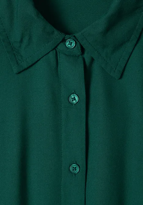 Donkergroene blouse met klassieke kraag en centrale knoopsluiting.