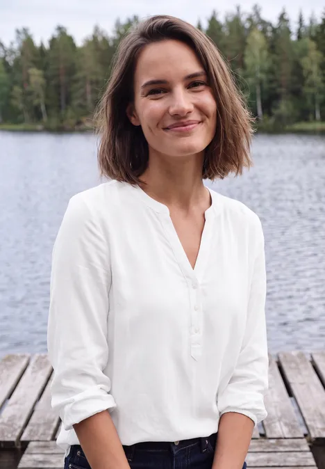 Langarm Tunika mit Split Neck White Junge Frau in weißer Bluse lächelt am Wasser, auf einem Holzsteg mit Wald im Hintergrund.