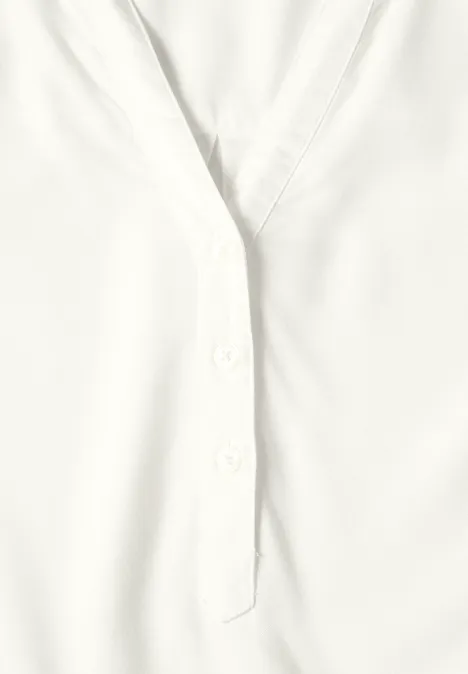 Nahaufnahme einer weißen Bluse mit Knopfleiste und V-Ausschnitt.