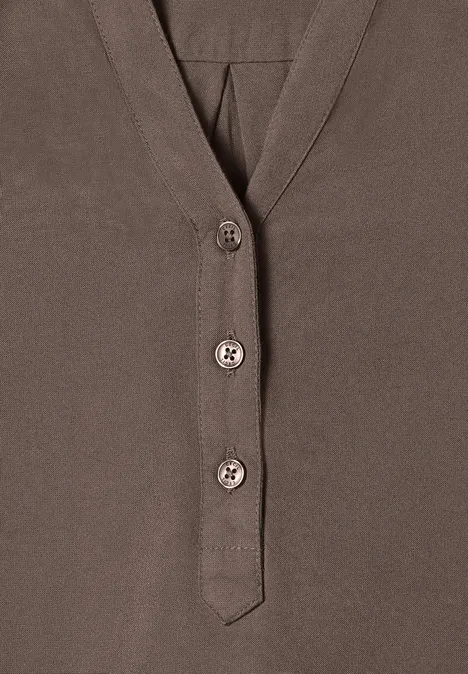 Bruin shirt met V-hals en drie knopen aan de voorkant.