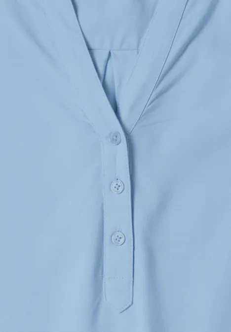 Lichtblauw shirt met V-hals en drie knopen.