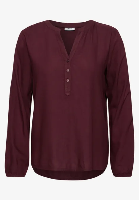 Bordeauxrode damesblouse met lange mouwen, V-hals en knoopsluiting, losse pasvorm.
