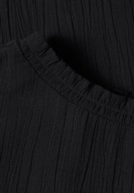 Nahaufnahme eines schwarzen, plissierten Stoffes mit elastischem Saum.